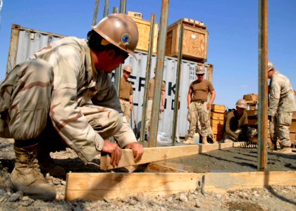 US Navy 100213-N-9564W-053 Steelworker Constructionman Jason Dalton and Builder 3rd Class Patrick Schneider level a concrete pad during a training day at Camp Krutke