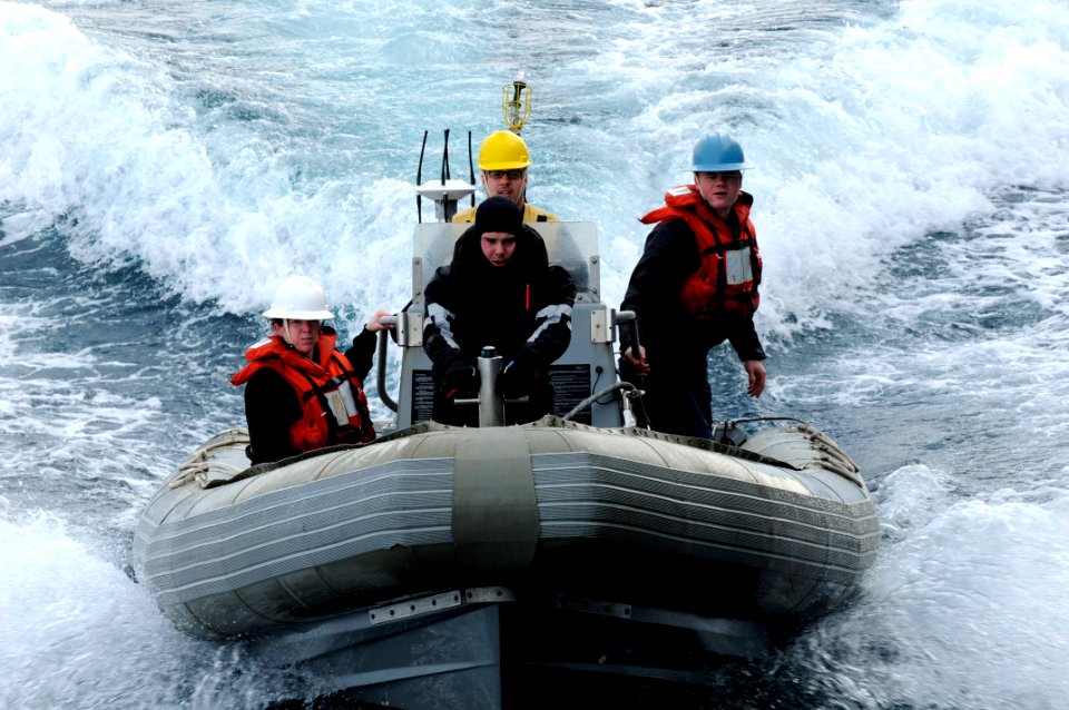 US Navy 100210-N-7478G-270 Information Systems Technician 2nd Class Kevin Abney, a search and rescue swimmer, holds on to the front of a rigid hull inflatable boat