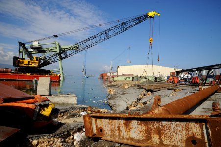 US Navy 100211-N-1134L-076 Workers aboard the tugboat Resolve Pioneer lower a section of damaged crane in the main seaport in Port-au-Prince, Haiti