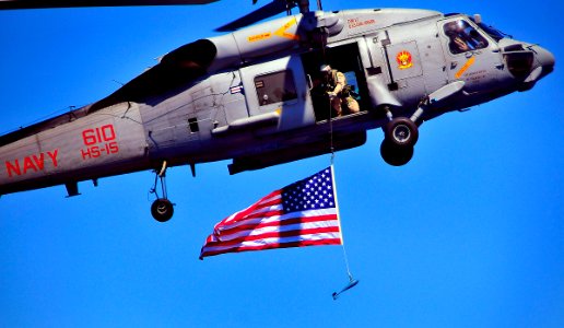 US Navy 100216-N-4774B-856 A member of the Explosive Ordnance Disposal Mobile Unit Group (EODMUG) 3 suspends an American flag from an SH-60F Sea Hawk helicopter