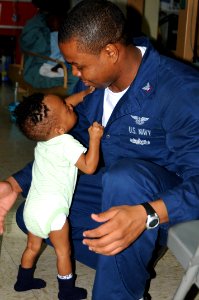 US Navy 100212-N-6410J-020 A Haitian child clings to Aviation Boatswains Mate (Handling) 3rd Class Pierre Toussaint in the pediatric ward aboard the Military Sealift Command hospital ship USNS Comfort (T-AH 20)