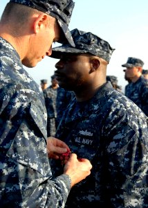 US Navy 100217-N-7638K-129 Cmdr. Nate Moyer pins the Bronze Star Medal on Operations Specialist 1st Class Anthony Ford