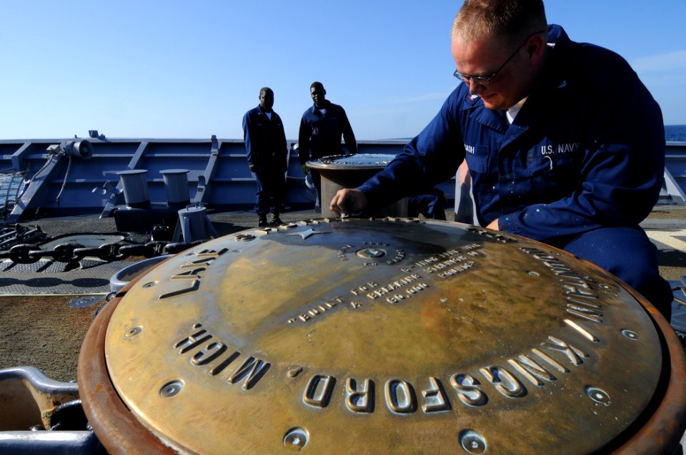 US Navy 100213-N-1688B-215 Boatswain's Mate 3rd Class Ryan Cash polishes the brass of a wildcat on the foc'sle of the guided-missile cruiser USS Hue City (CG 66)