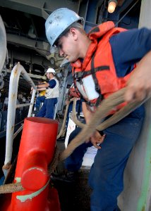 US Navy 100212-N-2000D-370 Boatswain's Mate 3rd Class Douglas Thomas wraps a line around a bit while securing a landing craft unit aboard USS Carter Hall (LSD 50)