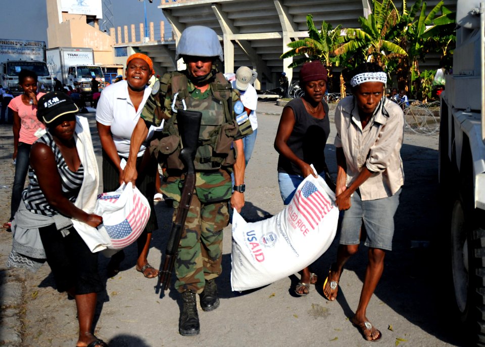 US Navy 100216-N-5961C-007 A U.N. peacekeeper from Argentina helps carry bags of rice during a humanitarian assistance distribution at Stade Sylvio Cator, the national soccer stadium, in Port-au-Prince, Haiti