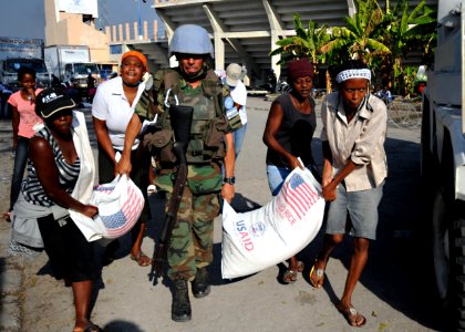 US Navy 100216-N-5961C-007 A U.N. peacekeeper from Argentina helps carry bags of rice during a humanitarian assistance distribution at Stade Sylvio Cator, the national soccer stadium, in Port-au-Prince, Haiti