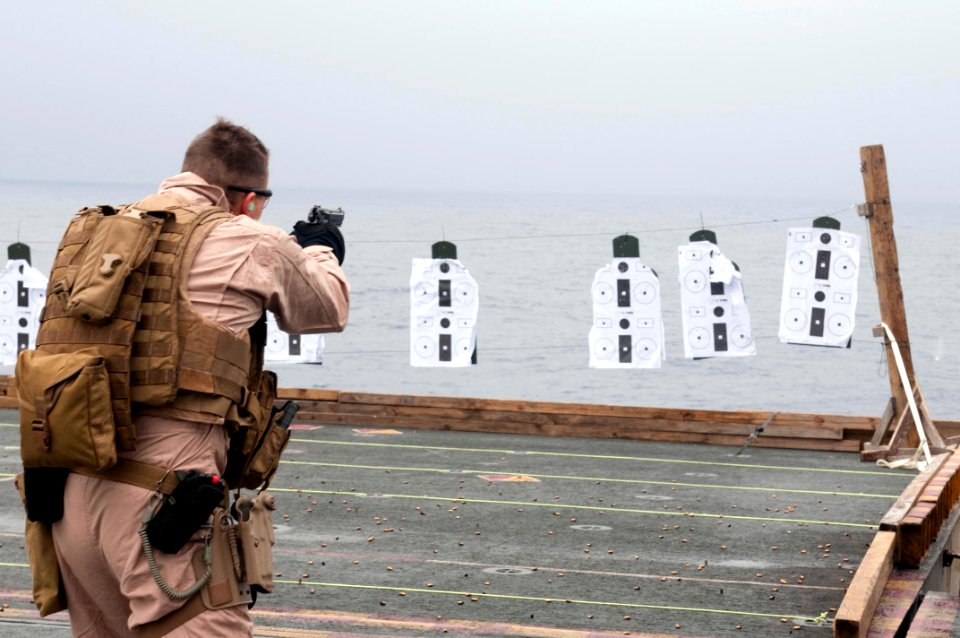 US Navy 100217-N-8936G-054 A Marine takes aims at a paper target during a pistol qualification on the flight deck of the amphibious assault ship USS Nassau (LHA 4)