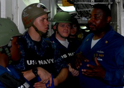 US Navy 100220-N-2000D-310 Chief Master-at-Arms Danel Harrison, from Columbia, S.C., assigned to the amphibious dock landing ship USS Carter Hall (LSD 50), instructs Sailors on clearing spaces during security reaction force bas