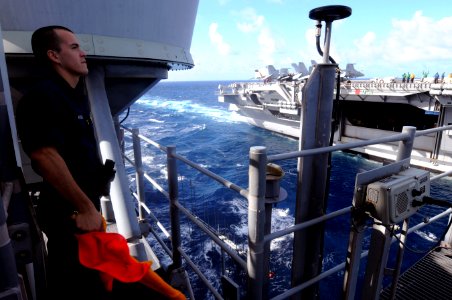 US Navy 100218-N-4275C-005 Quartermaster Seaman Matthew Rivera signals during a visual communications exercise aboard SS Bunker Hill (CG 52)