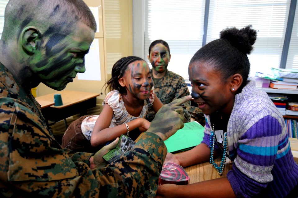 US Navy 100220-N-5328N-353 Pfc. Austin Natale, from Toledo, Wash., applies camouflage face paint on a student from Montclair Elementary School