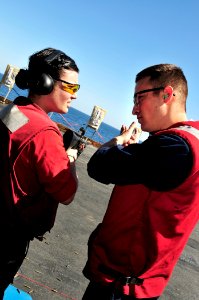 US Navy 100219-N-3595W-018 Gunners Mate Seaman Brian Aden shows Aviation Ordnanceman Kristen Miller proper shooting techniques during small arms qualifications aboard the aircraft carrier USS Dwight D. Eisenhower (CVN 69)