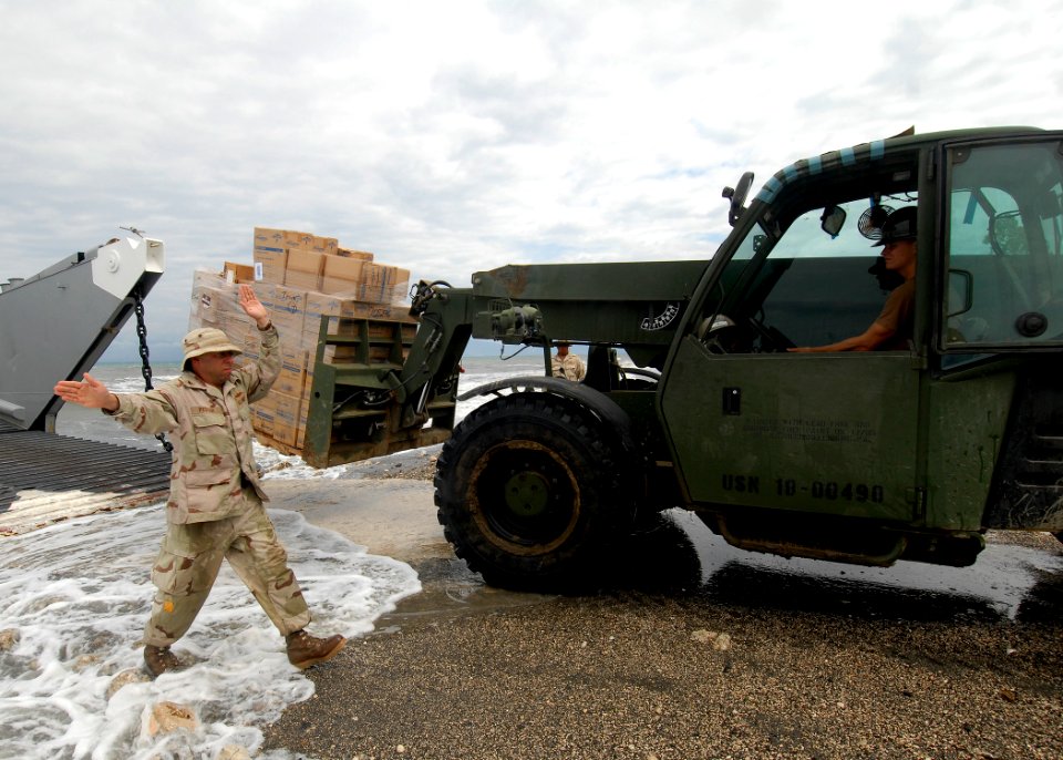 US Navy 100218-N-2000D-031 A Sailor assigned to Beach Master Unit (BMU) 2, left, directs a Seabee assigned to Amphibious Construction Battalion (ACB) 2 during a humanitarian supply delivery at New Mission Beach compound
