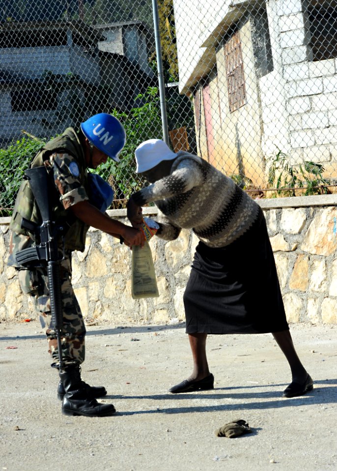 US Navy 100220-N-5961C-007 A U.N. peacekeeper from Nepal assists an elderly woman at a food distribution point in Kenscoff, Haiti