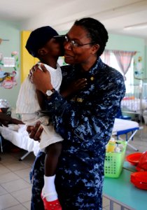 US Navy 100219-N-4995K-116 t. Toinette Evans, embarked aboard the Military Sealift Command hospital ship USNS Comfort (T-AH 20), embraces a young child in the pediatric ward of St. Damien Hospital in Port-au-Prince photo