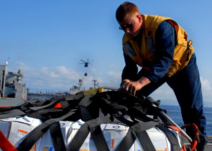 US Navy 100220-N-2000D-153 Boatswain's Mate 3rd Class Chris Rickerby, from Duluth, Ga., assigned to the amphibious dock landing ship USS Carter Hall (LSD 50), removes a cargo net from a pallet of supplies during a vertical repl