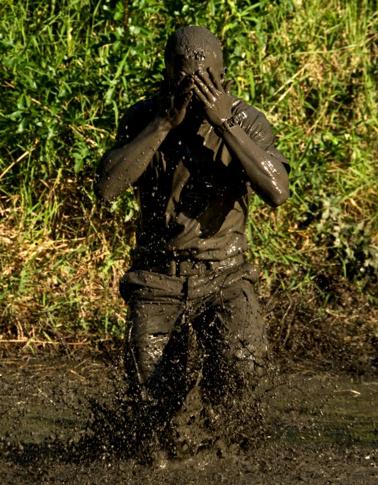 US Navy 100220-N-7498L-212 A participant wipes mud from his face after jumping in a pond during the 16th annual Swamp Romp