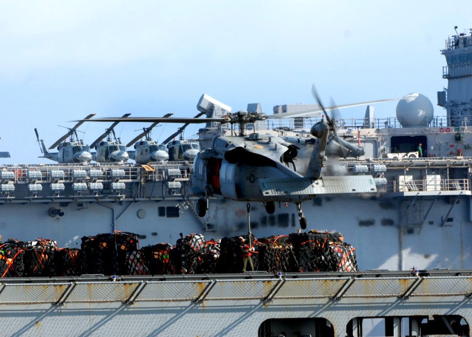 US Navy 100220-N-2000D-241 A merchant seaman aboard the Military Sealift Command dry cargo and ammunition ship USNS Sacagawea (T-AKE-2) hooks a pallet of supplies to the bottom of an MH-60S Sea Hawk helicopter