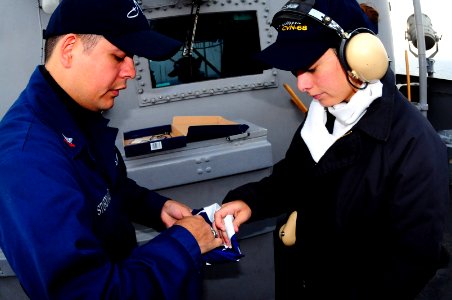 US Navy 100222-N-7939W-196 Quarter Master 2nd Class Ramon Sturdivant teaches Quarter Master Seaman Andrea Martinez how to fold a flag aboard the aircraft carrier USS Nimitz (CVN 68) photo