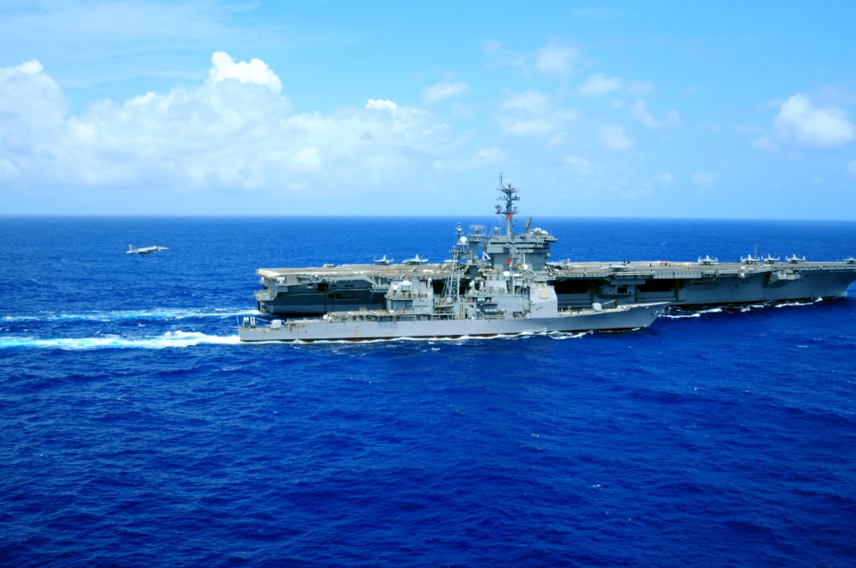 US Navy 100221-N-0808V-381 An F-A-18 Super Hornet assigned to Strike Fighter Squadron (VFA) 81 lands aboard the aircraft carrier USS Carl Vinson (CVN 70) as the guided-missile cruiser USS Bunker Hill (CG 52) pulls alongside