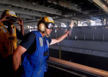 US Navy 100223-N-2000D-115 Seaman Jordan Luesebrink of South Sioux City, Neb., as he signals to the pilot of an air-cushioned landing craft (LCAC) during amphibious operations in the well deck of the amphibious dock landing shi photo