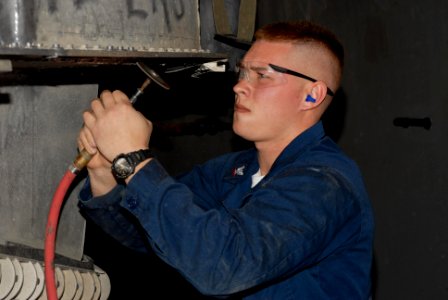 US Navy 100222-N-3358S-036 Hull Technician 3rd Class Kyle Skinner grinds off salt and corrosion on Landing Craft Air Cushion (LCAC) 87