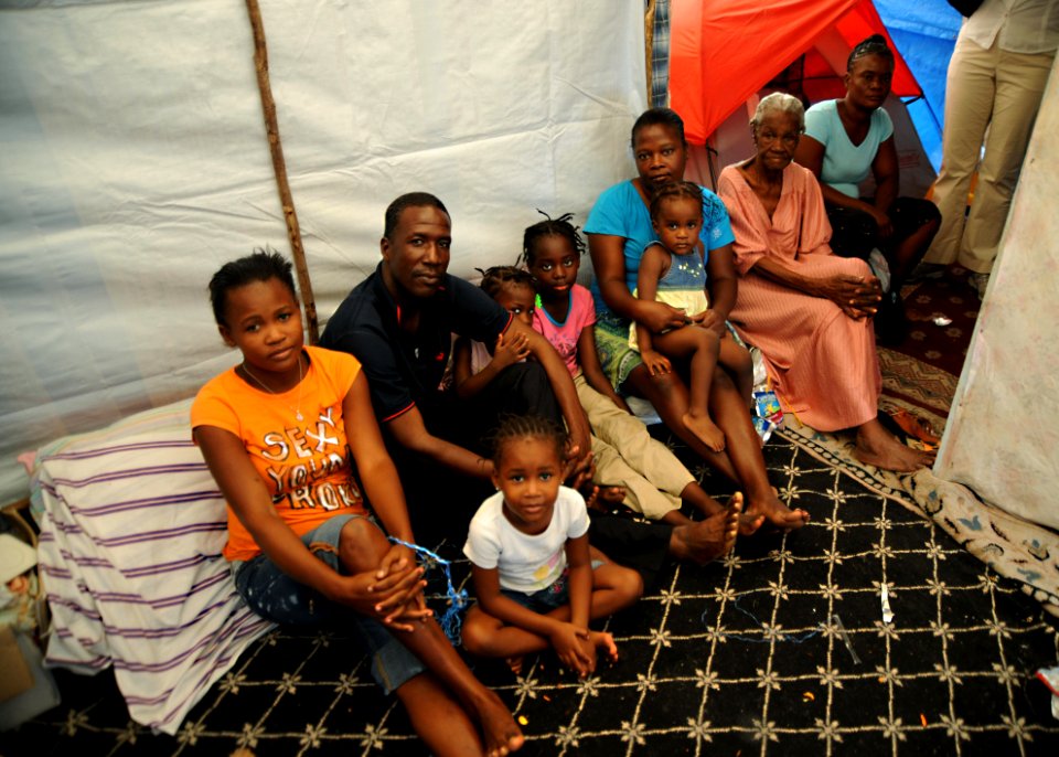 US Navy 100222-N-5961C-005 Jean Marc builds a temporary shelter with saplings and pieces of tarp. He salvaged rugs from his collapsed home to place on the ground for his family