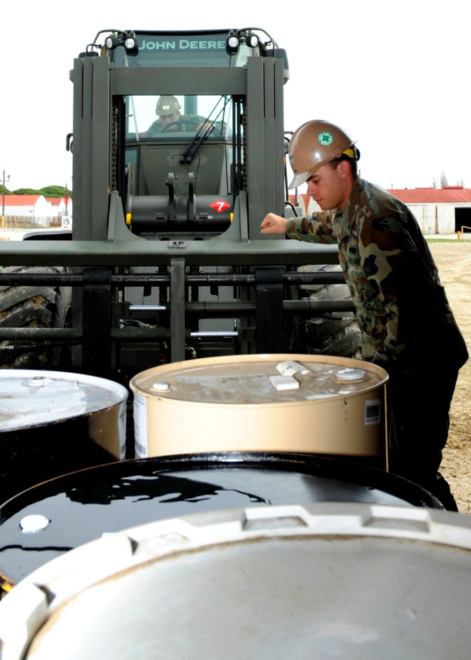 US Navy 100226-N-6357K-001 Equipment Operator 3rd Class AJ Dunn directs Equipment Operator Constructionman Apprentice Tyler Martin as he operates a 12K forklift to load materials