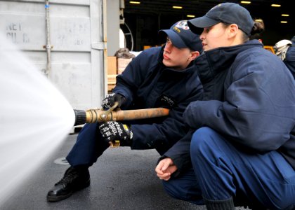 US Navy 100223-N-9626Y-002 Seaman Justin Kubitz, left, receives hose handling training during a general quarters drill aboard the aircraft carrier USS George Washington (CVN 73)
