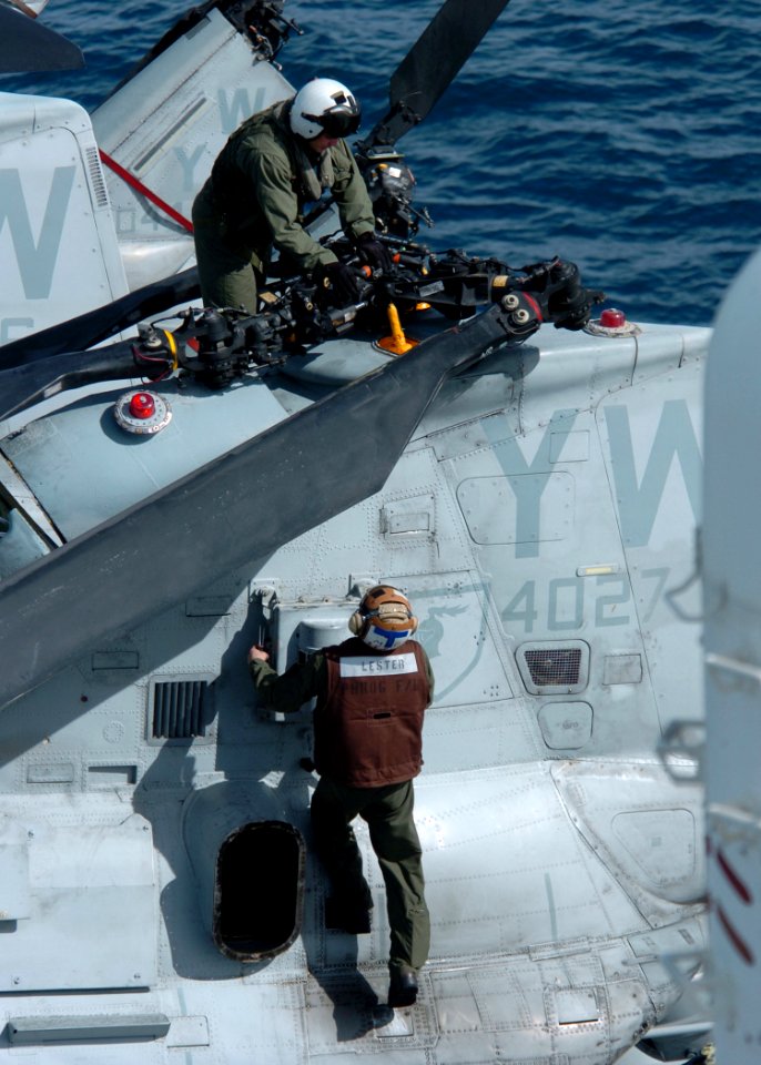 US Navy 100223-N-7948R-003 A Marine Corps pilot and crew chief conduct preflight safety checks on their aircraft before flight operations aboard the amphibious assault ship USS Peleliu (LHA 5)