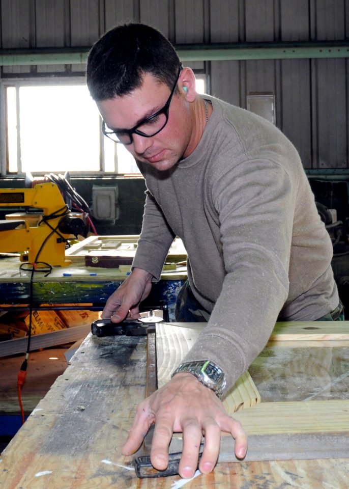 US Navy 100224-N-6357K-005 Builder 3rd Class Greg Lever, from Londonderry, N.H., assigned to Naval Mobile Construction Battalion (NMCB) 7, assembles a picture frame to be used in the refurbished Camp Mitchell chaplain's office