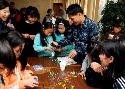 US Navy 100224-N-8721D-002 Culinary Specialist 3rd Class George Macapagal of Aurora, Ill., takes a picture of artwork created by students from the Yamamoto Elementary school during Kid's Craft Day