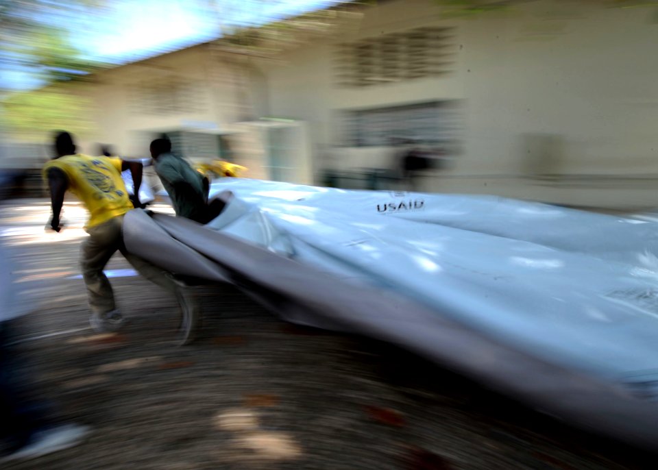 US Navy 100224-N-5961C-002 Haitian citizens run out a piece of plastic sheeting to be cut. The sheeting is being distributed in the Port-au-Prince area for people affected by the Jan. 12 earthquake
