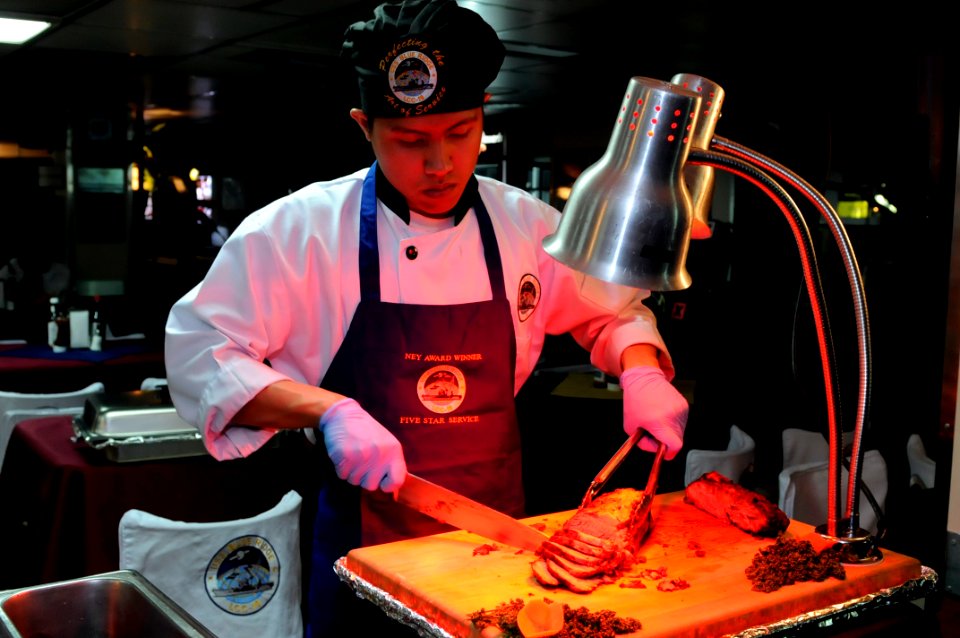 US Navy 100225-N-7478G-035 Culinary Specialist Seaman Mikhail Mendoza slices roast beef during a family appreciation meal aboard the U.S. 7th Fleet command ship USS Blue Ridge (LCC 19)
