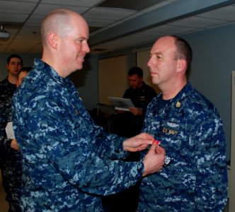 US Navy 100224-N-3090M-123 Cmdr. Charles Maher, commanding officer of the fast attack submarine USS Memphis (SSN 691), pins a Bronze Star medal on the uniform of Chief Electronics Technician William Cox Jr