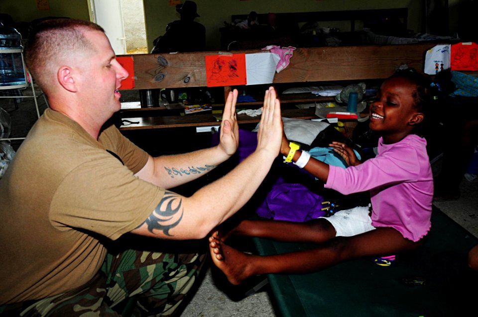 US Navy 100228-N-9643W-026 A Sailor assigned to Naval Beach Group (NBG) 2 plays with a Haitian girl at the New Life Children's Home in Port-au-Prince, Haiti