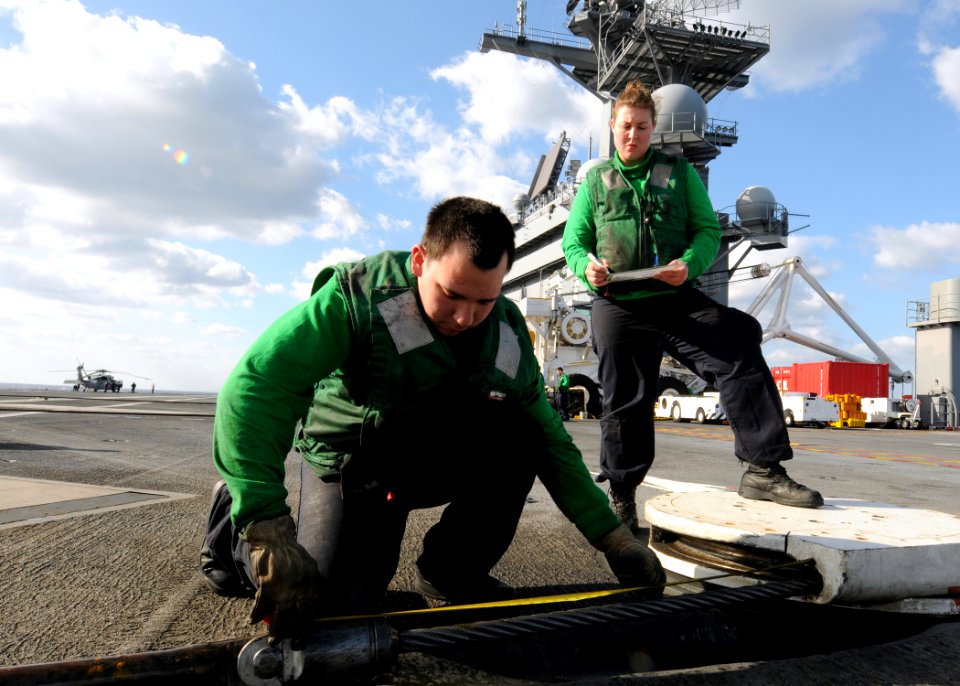 US Navy 100228-N-9116S-040 Aviation Boatswain's Mate (Equipment) Airmen Santiago Garcia, left, and Carissa M. Smith, measure cross deck pendant cable short-ends on the flight deck of the aircraft carrier USS George H.W. Bush (C