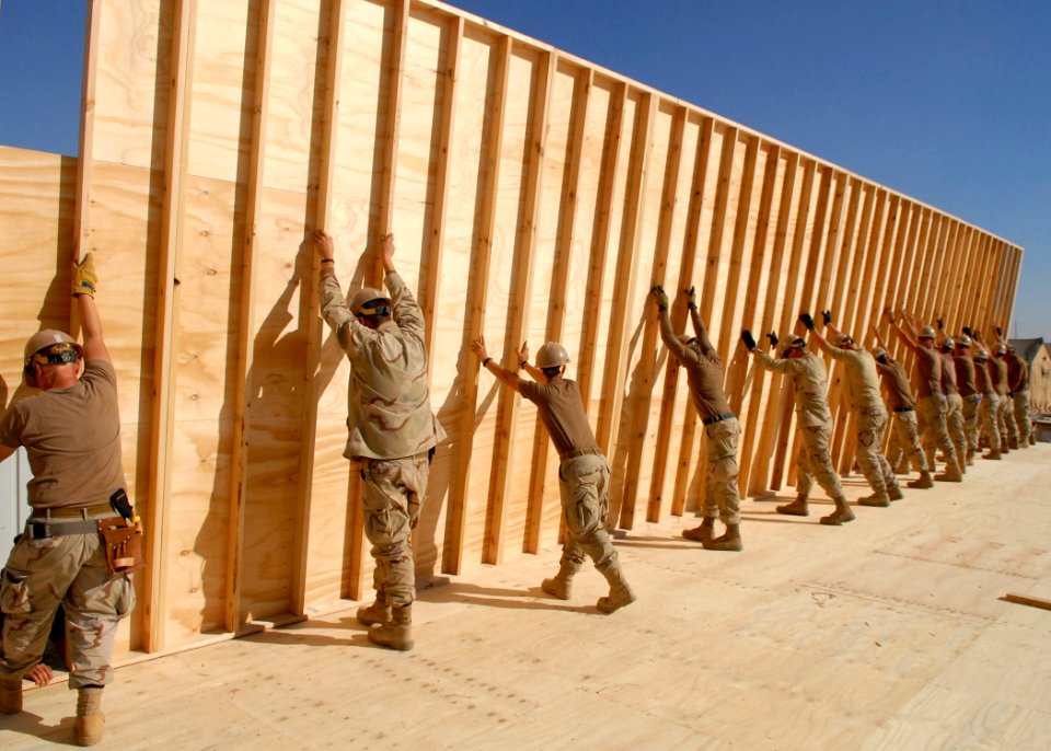 US Navy 100301-N-4440L-196 Seabees assigned to Naval Mobile Construction Battalion (NMCB) 74 and NMCB-4 raise a 12-foot wall section for a southwest Asia hut