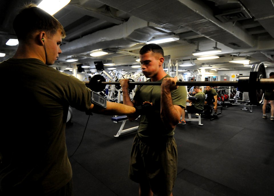 US Navy 100301-N-7948R-017 Lance Cpl. Kyle Kenner, right, from Arkansas, lifts weights in the gym aboard the amphibious assault ship USS Peleliu (LHA 5)