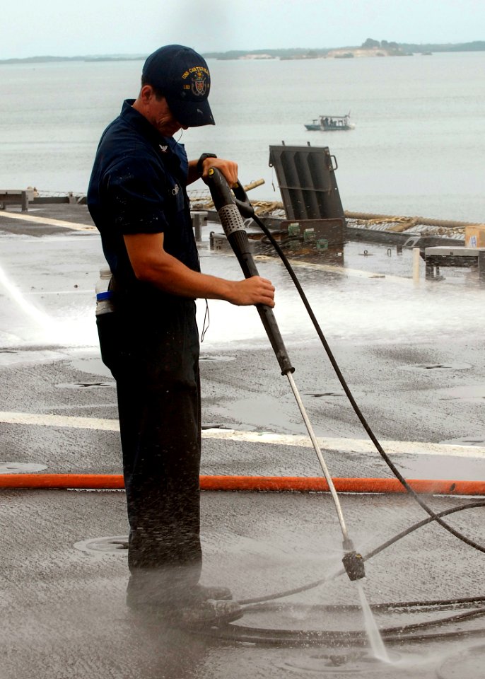 US Navy 100302-N-2000D-092 Boatswain's Mate 3rd Class Ryan Schuler sprays fresh water on the flight deck during an agricultural wash down aboard the amphibious dock landing USS Carter Hall (LSD 50)