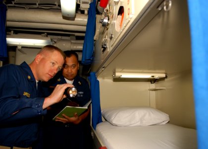 US Navy 100227-N-6692A-047 Chief Master-at-Arms Albert S. Spiess, left, inspects a berthing space as Culinary Specialist 1st Class Jun R. Gozon, berthing petty officer in-charge, logs discrepancies