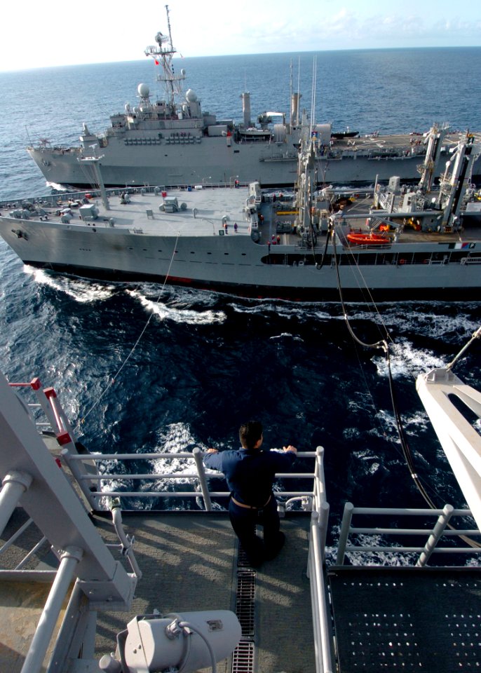 US Navy 100303-N-1226D-140 A Sailor aboard USS Peleliu (LHA 5) looks on as USNS Henry J. Kaiser (T-AO 187) supplies fuel to USS Peleliu (LHA 5) and USS Dubuque (LPD 8)