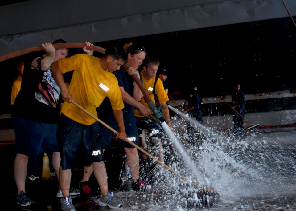 US Navy 100302-N-2000D-164 Sailors aboard the amphibious dock landing ship USS Carter Hall (LSD 50) use a fire hose and push brooms to scrub the well deck during an agricultural wash down