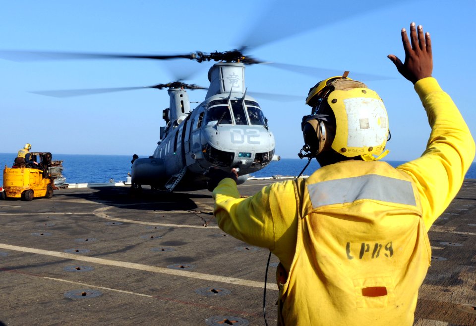 US Navy 100302-N-5538K-065 Aviation Support Equipment Technician Airman Tione M. Williams directs the loading of equipment into a CH-46E Sea Knight on the flight deck of the forward-deployed amphibious transport dock USS Denver