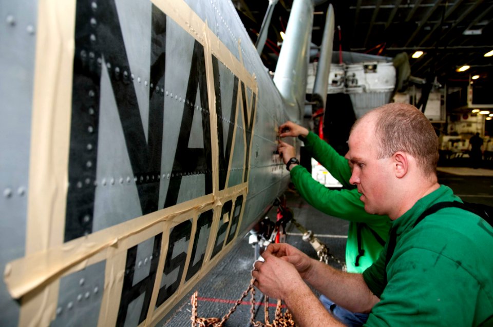 US Navy 100302-N-8936G-031 Aviation Structural Mechanic 2nd Class and Aviation Structural Mechanic 3rd Class Thomas Hall place tape on an MH-60S Sea Hawk helicopter during preparation for repainting