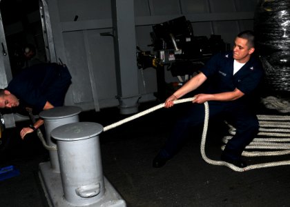 US Navy 100302-N-9116S-187 Boatswain's Mate 3rd Class Rene Barriere secures a line while lowering a rigid-hull inflatable boat