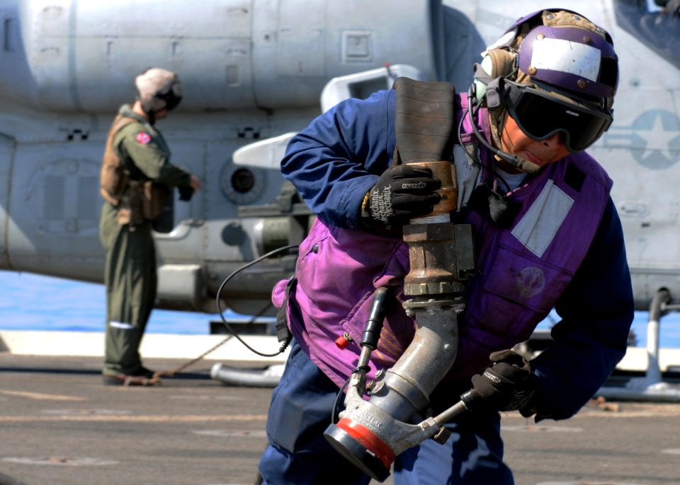 US Navy 100304-N-5538K-068 Aviation Boatswains Mate (Fuel) 2nd Class Ranulfo C. Gonzalez drags a JP-5 fuel hose after refueling an AH-1 Super Cobra helicopter