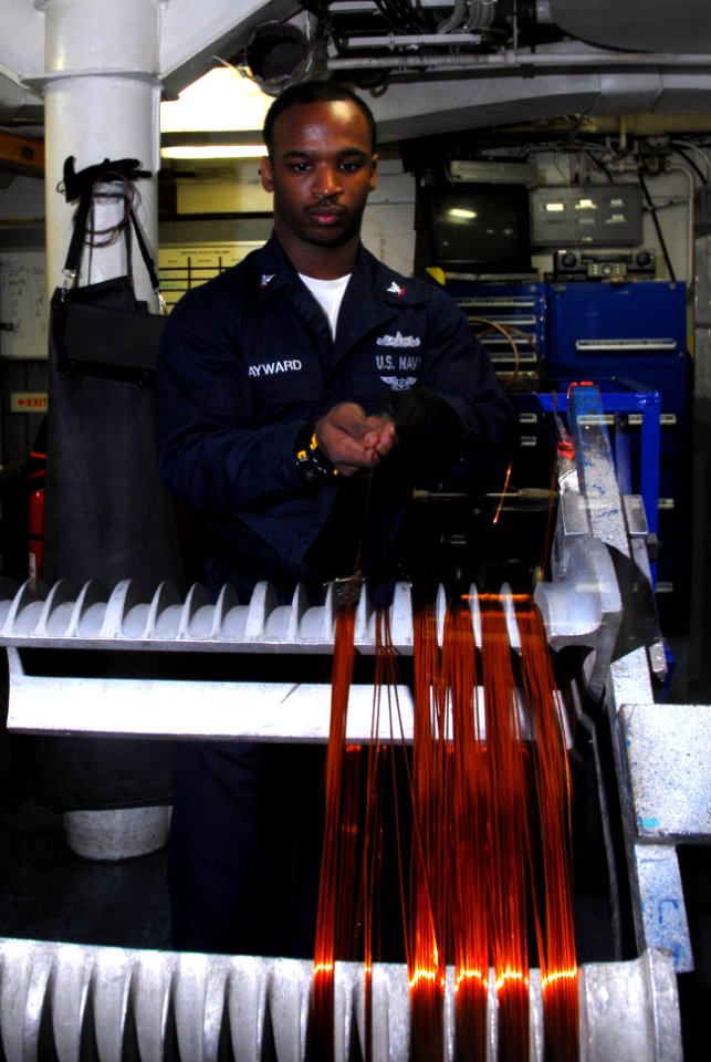 US Navy 100302-N-3327M-012 Electrician's Mate 3rd Class Tyreek Hayward winds copper wire for a ventilation motor during maintenance aboard the aircraft carrier USS Nimitz (CVN 68)