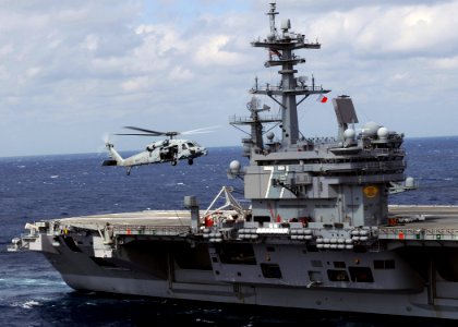 US Navy 100303-N-3885H-172 An MH-60S Sea Hawk helicopter flies alongside USS George H.W. Bush (CVN 77)
