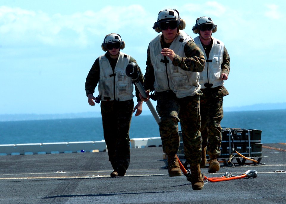 US Navy 100304-N-7948R-420 Marines remove straps from ammunition during an ammo on-load aboard the amphibious assault ship USS Peleliu (LHA 5)