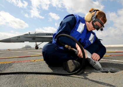 US Navy 100303-N-9793B-007 Aviation Boatswain's Mate (Handling) Airman Taylor L. Chandler performs restoration work on the ship's flight deck